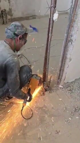 Construction worker cuts metal with grinder in Bat Yam