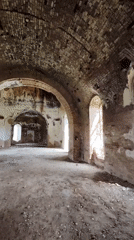 Woman explores abandoned brick building with arched architecture