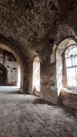 Woman explores abandoned brick building with arched architecture