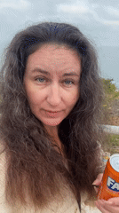 Woman enjoys morning ocean view with soda in Netanya