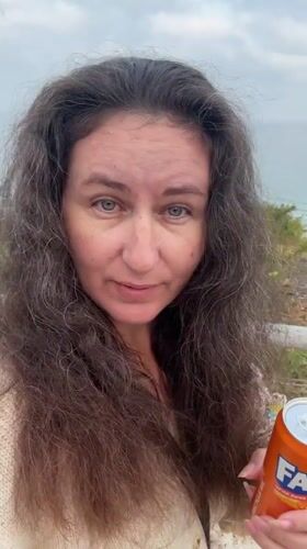 Woman enjoys morning ocean view with soda in Netanya