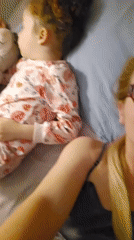 Mother blows kiss to camera while lying with child