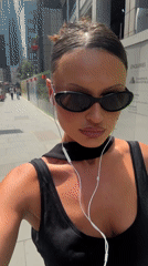Woman with headphones strolls London sidewalk carrying shopping bag