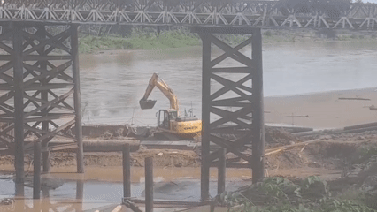 Excavator works riverbank construction under bridge in Indonesia