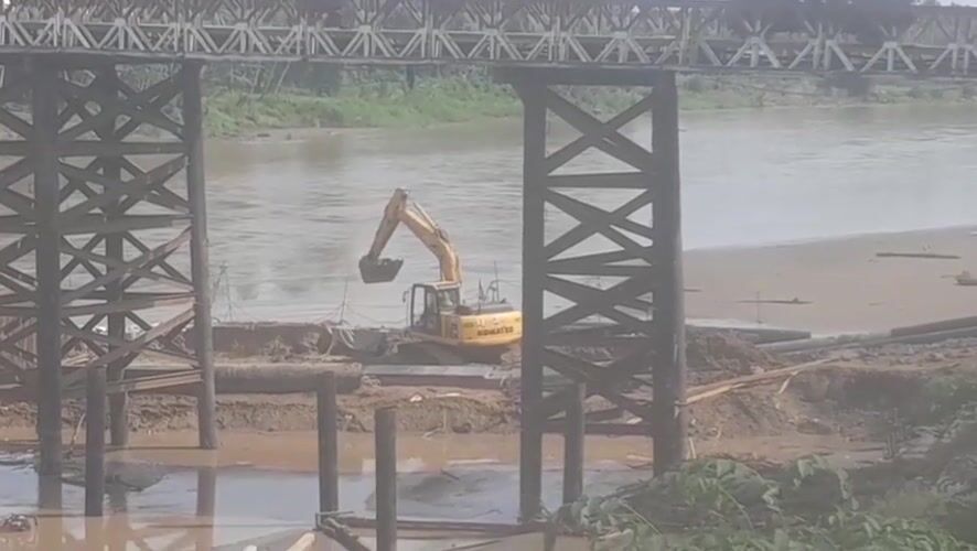 Excavator works riverbank construction under bridge in Indonesia