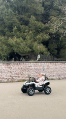 Children ride toy car along road in Bar, Montenegro