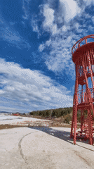 Woman visits red lighthouse tower by frozen lake in Ust-Ilimsk