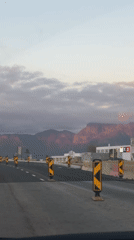 Vehicle travels Paarl road with pink-hued mountains visible