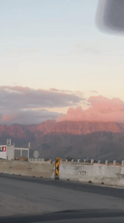 Vehicle travels Paarl road with pink-hued mountains visible