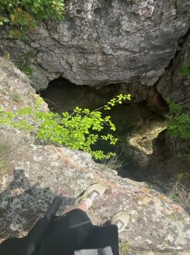 Two people explore natural sinkhole near cliffs in Ruse