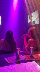 Two women enjoy karaoke session in colorful lighting