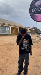 Young man dances, poses with phone outdoors
