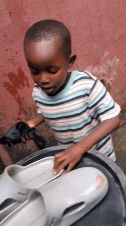 Toddler plays and rests near shoes outside a Jos home