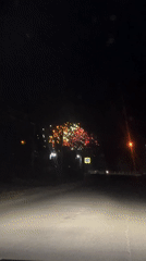 Driver films nighttime fireworks display from rural roadway