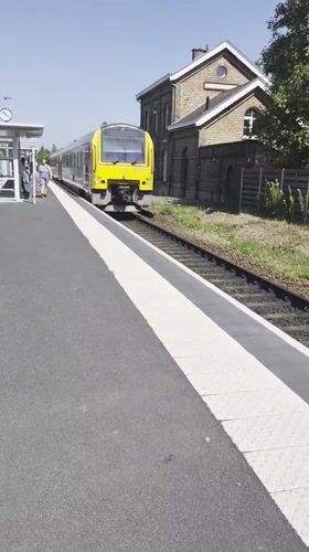 Train arrives at Evergem station on a sunny morning