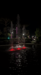 Red-lit fountain operates in park during nighttime hours