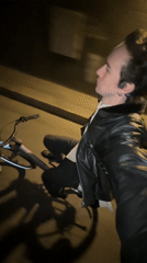 Nighttime cyclist in leather jacket observed riding bicycle