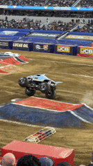 Monster trucks perform jumps at packed stadium event