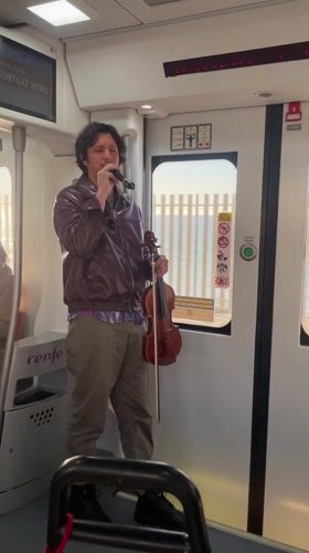 Street musician performs with violin on Spanish train