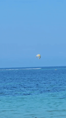 Kiteboarders, boats, and beach life on a calm Bali morning