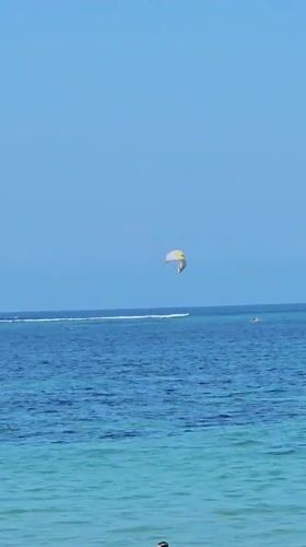 Kiteboarders, boats, and beach life on a calm Bali morning