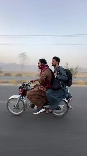 Red motorcycle with two riders on a paved road in Milozo