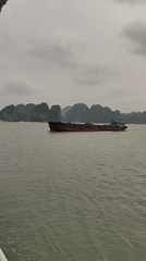 Barge crosses Ha Long Bay waters under overcast skies