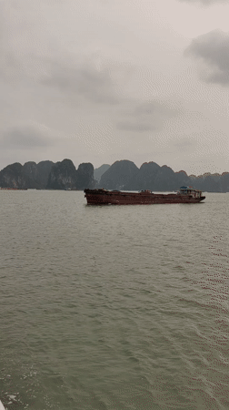Barge crosses Ha Long Bay waters under overcast skies