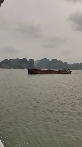 Barge crosses Ha Long Bay waters under overcast skies