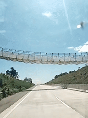 Vehicle passes under netting barrier on Indonesian highway
