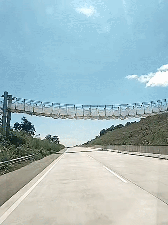 Vehicle passes under netting barrier on Indonesian highway