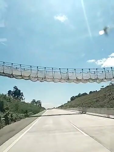Vehicle passes under netting barrier on Indonesian highway
