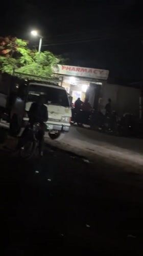 Nighttime street gathering recorded near pharmacy in Bukuru, Nigeria
