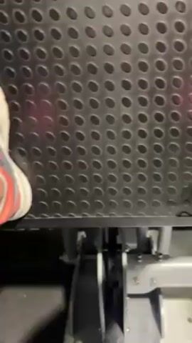 The video shows a leg press machine in use, starting with a close-up of the footplate and a person's feet in sneakers. The camera angle moves to show the weight stack, with labels indicating the weight in pounds and kilograms.  The weight stack is black, with white lettering. The machine is in a gym setting.