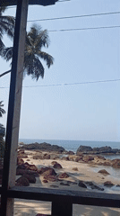 Man observed on balcony overlooking Querim beach early morning