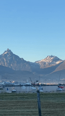 Clear skies over snow-capped mountains and boats in Ushuaia harbor