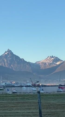 Clear skies over snow-capped mountains and boats in Ushuaia harbor