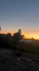 Sunset light falls over a rural greenhouse and open land
