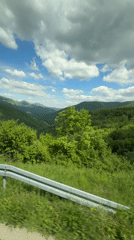 Passenger films green mountains from car window in Bosnia