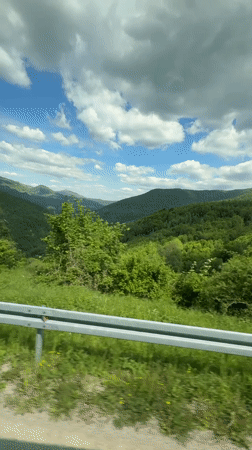 Passenger films green mountains from car window in Bosnia