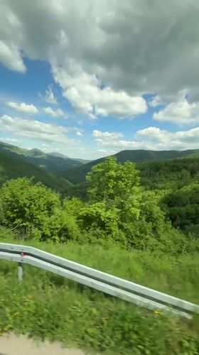 Passenger films green mountains from car window in Bosnia