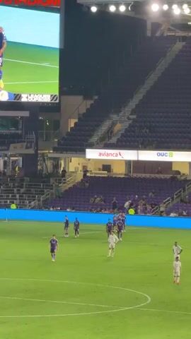 The video captures a soccer match at a stadium at night. The large scoreboard displays the score as 2-0 with the game clock at 68:35. The field is illuminated, and the stands, mostly filled with spectators, are visible in the background. Several players in white and purple uniforms are on the green field. On the big screen, two players in purple uniforms are embracing, with a circular, abstract graphic obscuring part of the image. The stadium's name, "INTER CO. STADIUM," is prominently displayed on the scoreboard. Advertising banners for "Sherwin-Williams" and "El Aliad del PRO" are visible along the edge of the field. The overall atmosphere appears to be that of a professional sporting event.