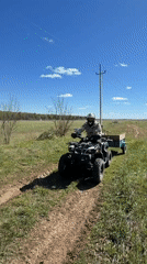 ATV operator with trailer crosses field in rural Russia