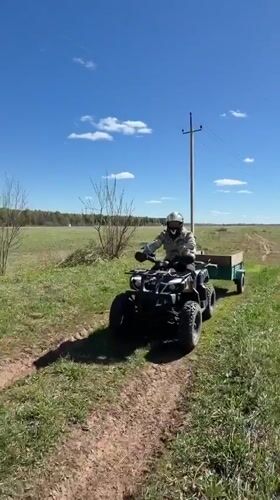 ATV operator with trailer crosses field in rural Russia