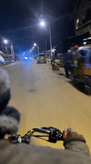 Motorcycle rider travels illuminated Bukuru streets at night