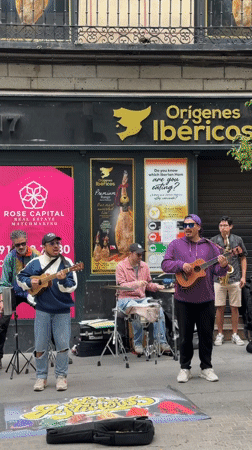 Street musicians perform outside Madrid shop with ukuleles, drums