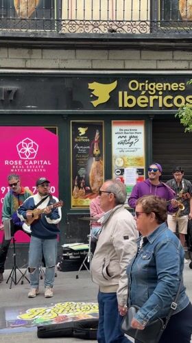 Street musicians perform outside Madrid shop with ukuleles, drums