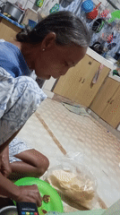 Elderly woman enjoys meal on floor in Baron, Indonesia