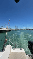 White fishing boat navigates Spanish harbor on sunny morning