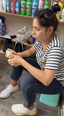 Woman sits on stool in cluttered Tashkent room